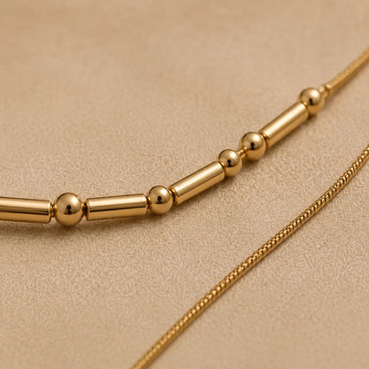 Gold necklace with beads on a beige background