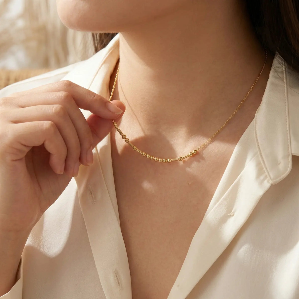 Close-up of a person wearing a gold necklace with a blurred background